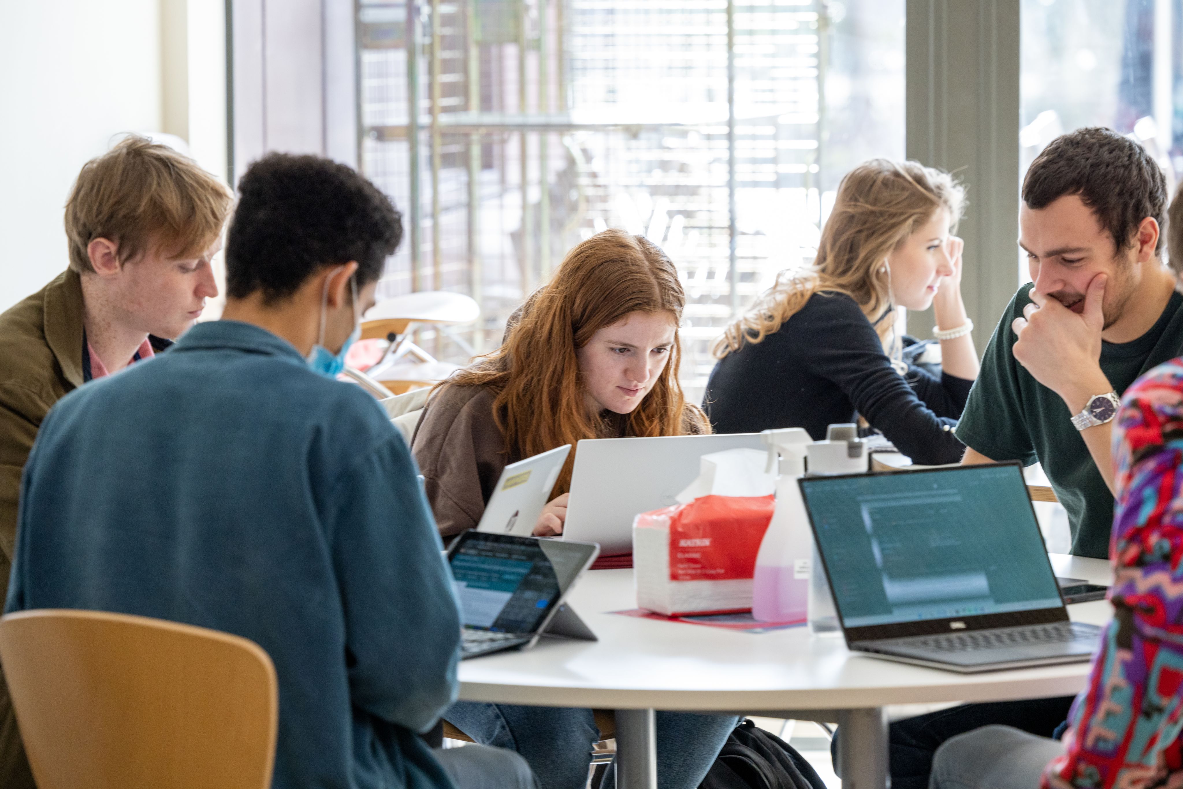 Four people sat round a table with laptops in a cafe setting