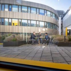 Group of three students chatting in internal courtyard of CEB