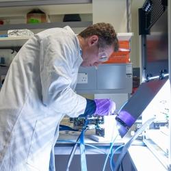 Man in white coat working on electronic device