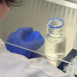 Researcher in white lab coat pipettes liquid into sample box