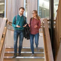 Two students walking down the central staircase chatting