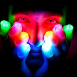 a person with their hands on their face with multi-coloured lights in the dark